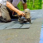 Man working on a roof nailing tiles.