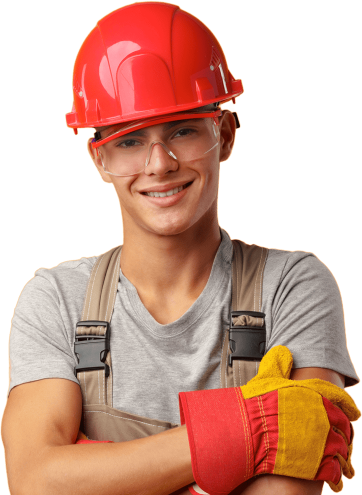 Young man in red hard hat, wearing glasses and overalls, smiling and posing for the camera.