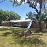 Residential single story home with newly white metal roof in the process of being installed.