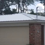 Residential single story home with newly white metal roof in the process of being installed.