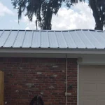 Residential single story home with newly white metal roof in the process of being installed.