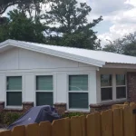 Residential single story home with newly white metal roof in the process of being installed.