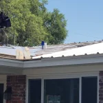 Residential single story home with newly white metal roof in the process of being installed.